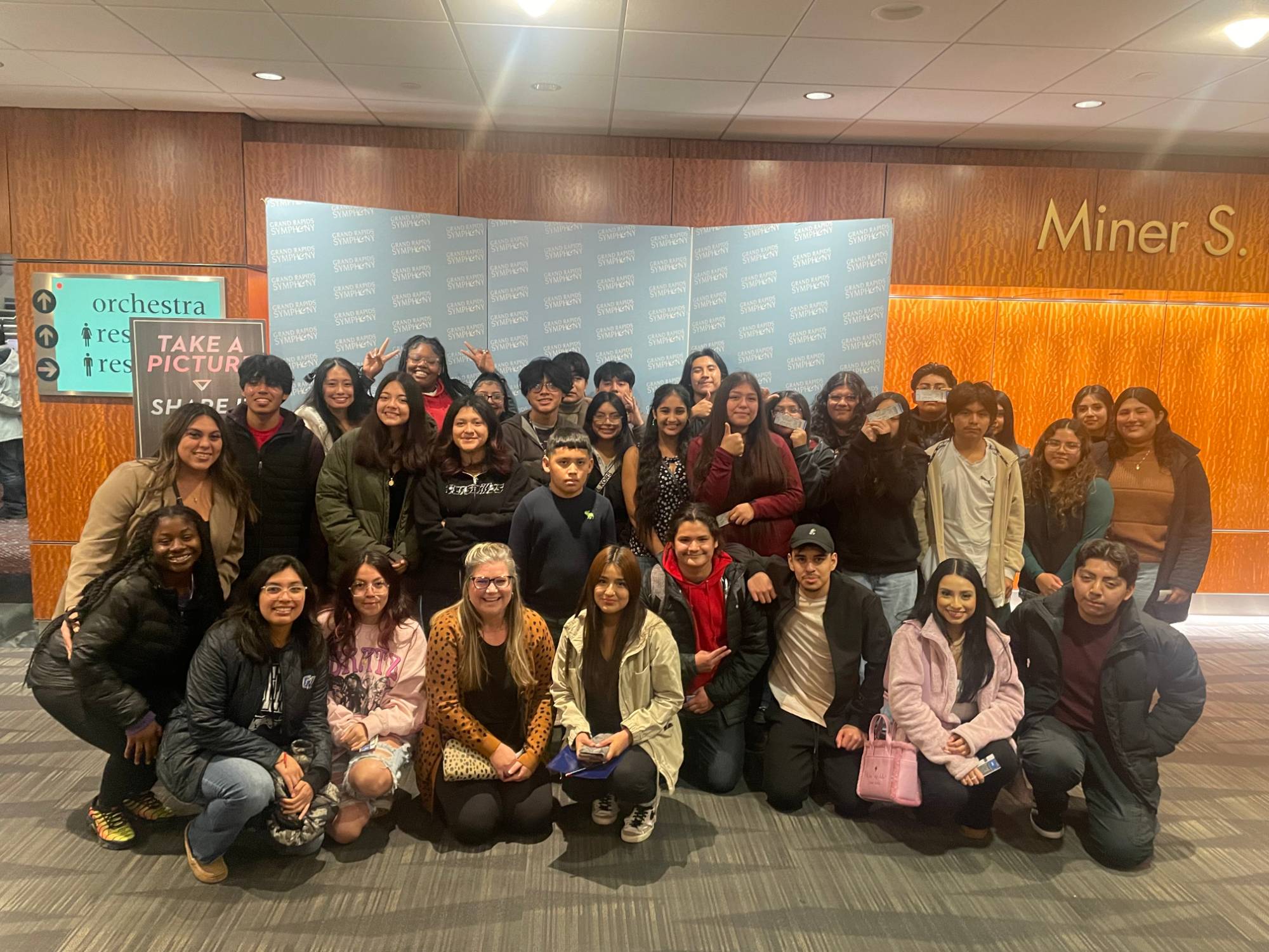 A group of students in front of a Grand Rapids Symphony backdrop